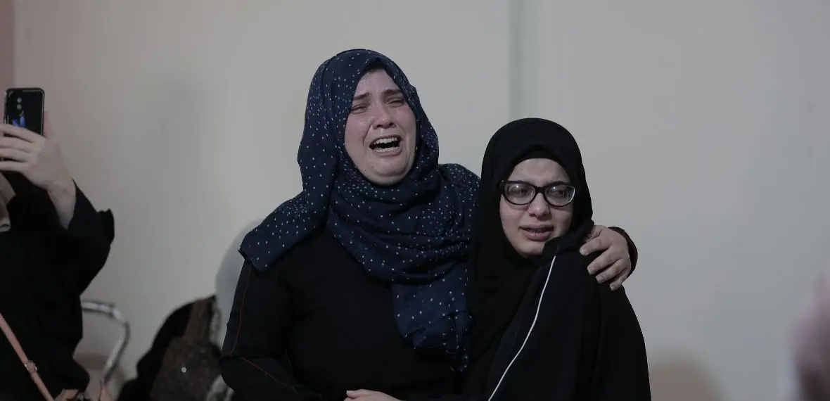 Two women in black attire stand together indoors, showing support during a Giving Hands event.